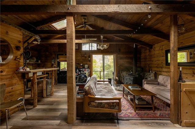 living room with hardwood / wood-style flooring, a wood stove, beam ceiling, ceiling fan, and wooden ceiling