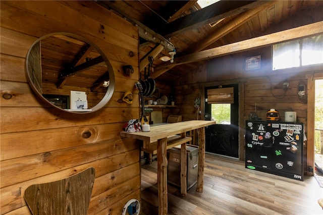 interior space with vaulted ceiling with beams, wood walls, hardwood / wood-style floors, and a wealth of natural light