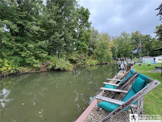 view of dock with a lawn and a water view