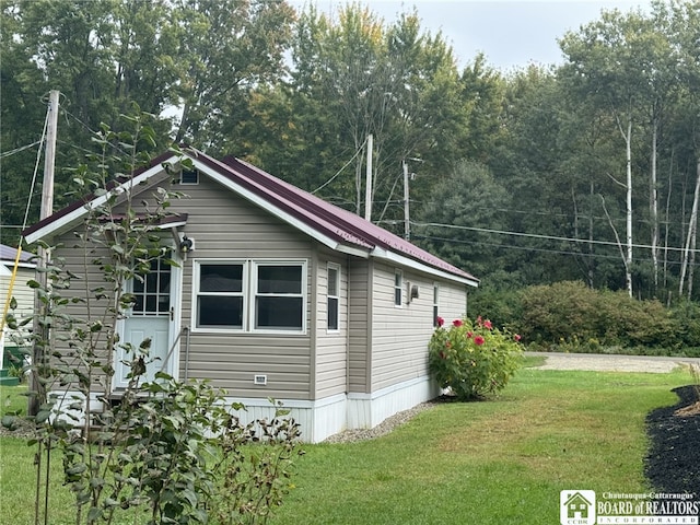 view of side of home with metal roof and a lawn