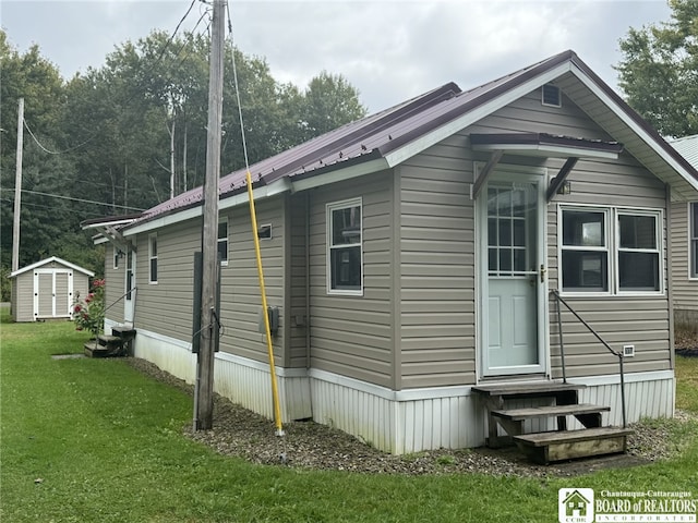 view of home's exterior featuring entry steps, a yard, metal roof, and an outbuilding