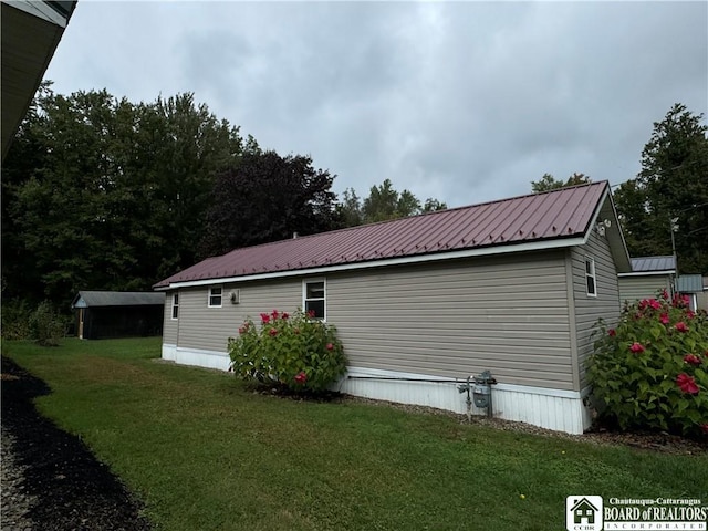 view of side of home with metal roof and a yard