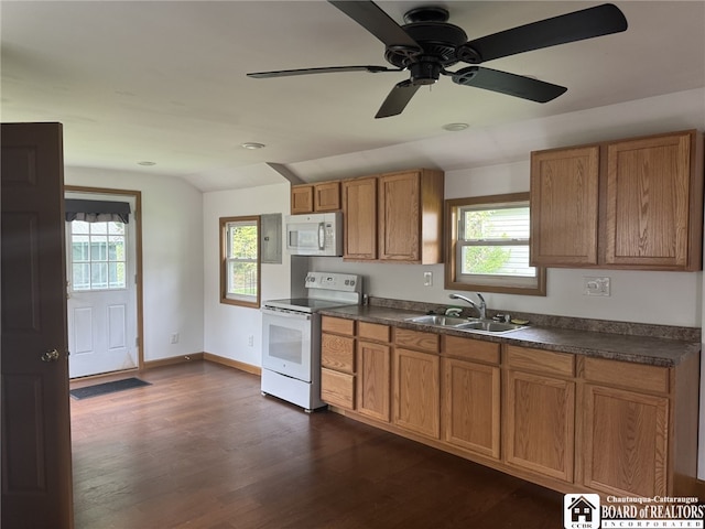 kitchen featuring white appliances, brown cabinetry, dark countertops, and a sink