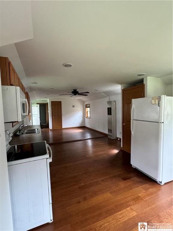 kitchen featuring brown cabinetry, ceiling fan, a sink, wood finished floors, and white appliances