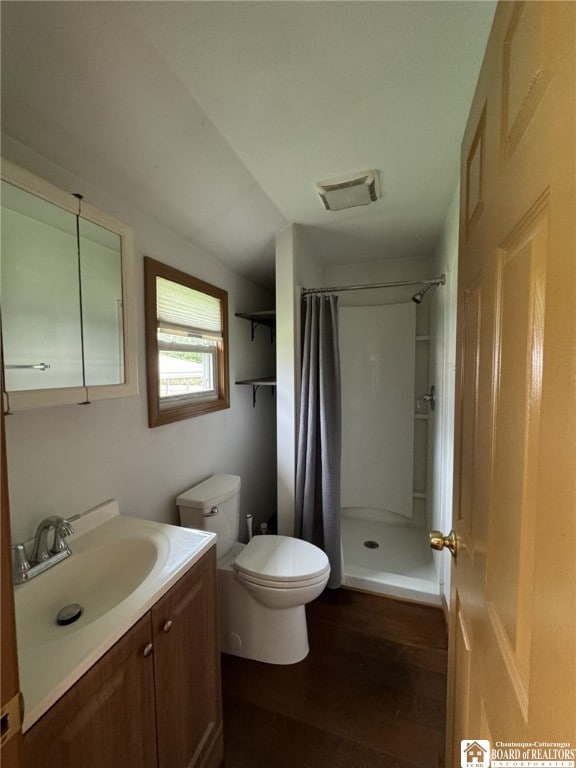 bathroom with visible vents, toilet, a shower with shower curtain, vanity, and wood finished floors