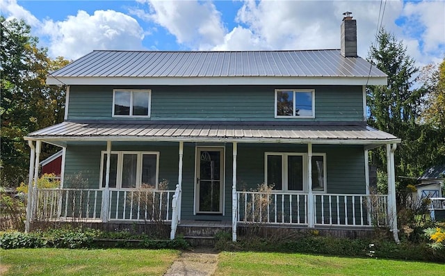 view of front of home with a chimney, a porch, and metal roof