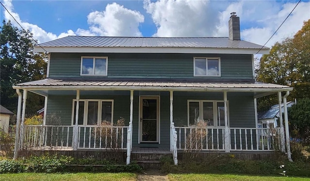rear view of property featuring covered porch, metal roof, and a chimney