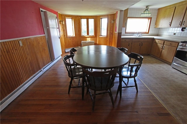 dining room with wood walls, baseboard heating, and dark hardwood / wood-style flooring