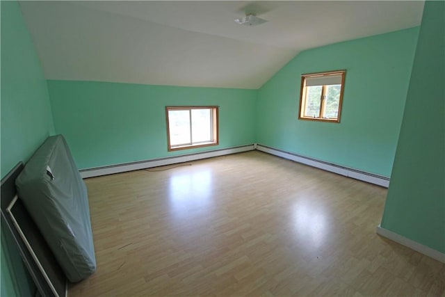 additional living space with plenty of natural light, baseboard heating, and wood finished floors