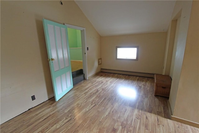 unfurnished room featuring wood finished floors, vaulted ceiling, and baseboard heating