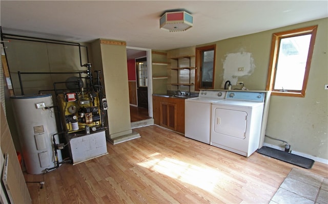 laundry area featuring cabinets, water heater, light hardwood / wood-style flooring, and washer and dryer