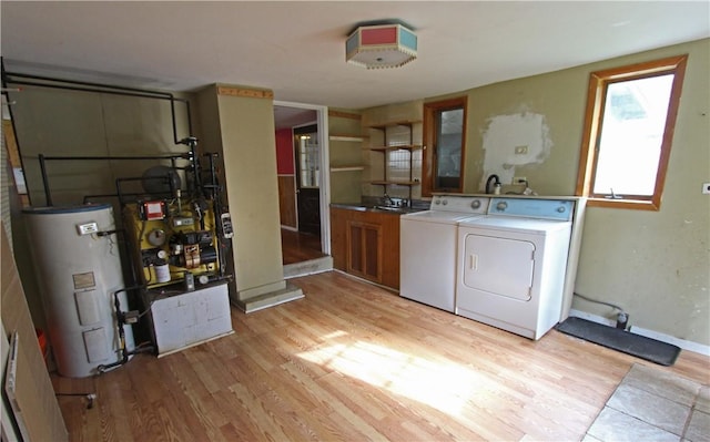 washroom featuring washing machine and dryer, a sink, light wood-style floors, cabinet space, and electric water heater