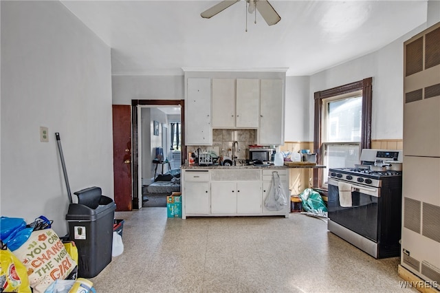 kitchen featuring backsplash, ceiling fan, stainless steel range with gas stovetop, and white cabinets