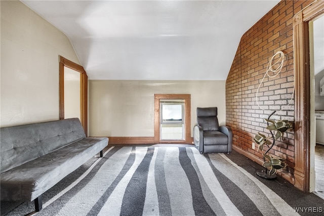 unfurnished room with lofted ceiling, dark colored carpet, and brick wall