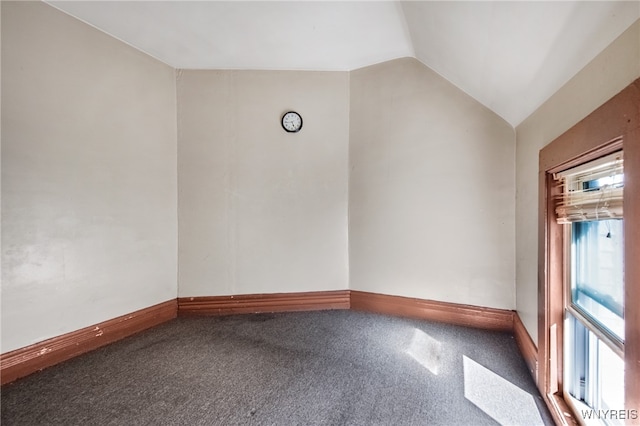 carpeted empty room with vaulted ceiling