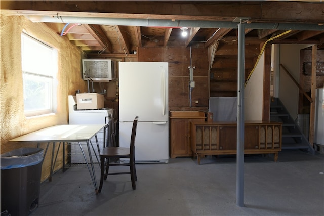 basement featuring water heater, white fridge, and washer / dryer