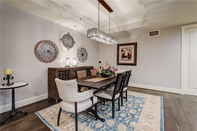 dining room featuring a raised ceiling and dark wood-type flooring