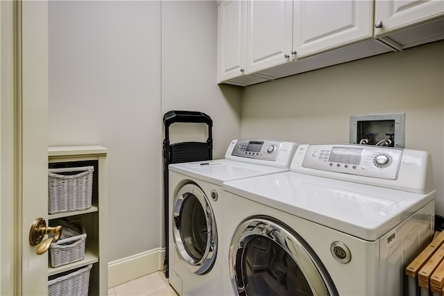 laundry room featuring washer and clothes dryer, light tile patterned floors, and cabinets