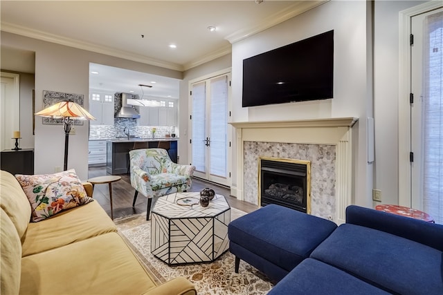 living room with light wood-type flooring, ornamental molding, and a premium fireplace