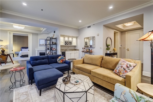 living room with light hardwood / wood-style flooring, wine cooler, bar, and crown molding