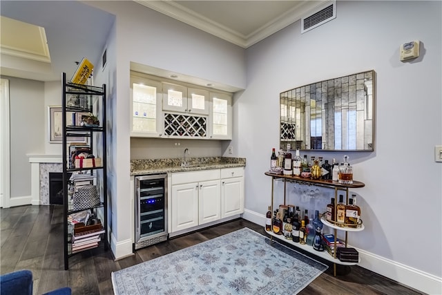 bar featuring crown molding, white cabinetry, beverage cooler, and dark hardwood / wood-style flooring