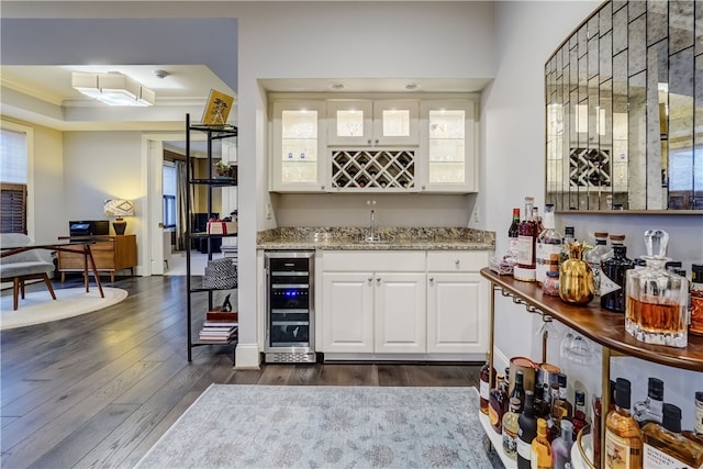 bar featuring crown molding, wine cooler, white cabinetry, and dark hardwood / wood-style flooring