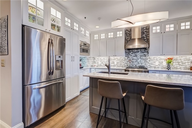 kitchen featuring sink, white cabinetry, wall chimney exhaust hood, appliances with stainless steel finishes, and light stone countertops