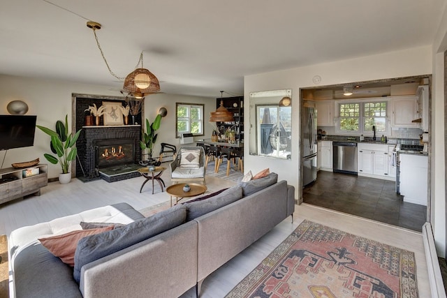 living room with a brick fireplace, hardwood / wood-style floors, and sink