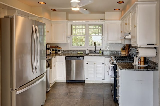 kitchen with dark stone counters, stainless steel appliances, white cabinetry, and sink