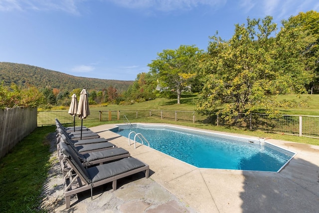 view of pool with a patio, a yard, and a mountain view