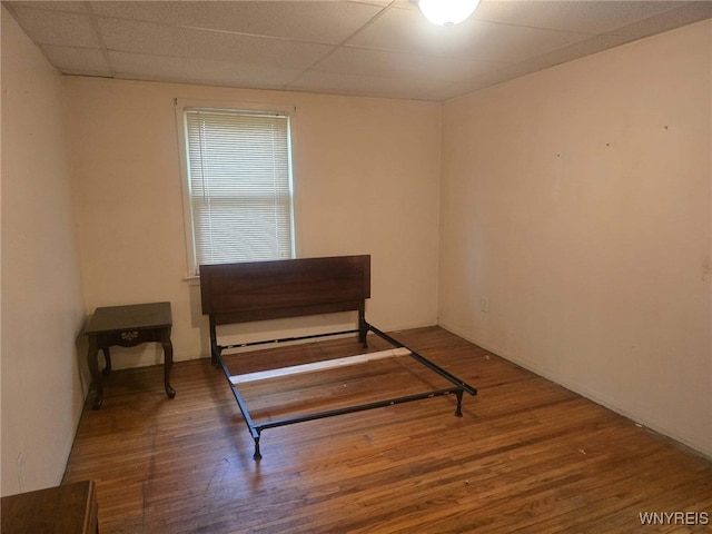 living area featuring a drop ceiling and wood-type flooring