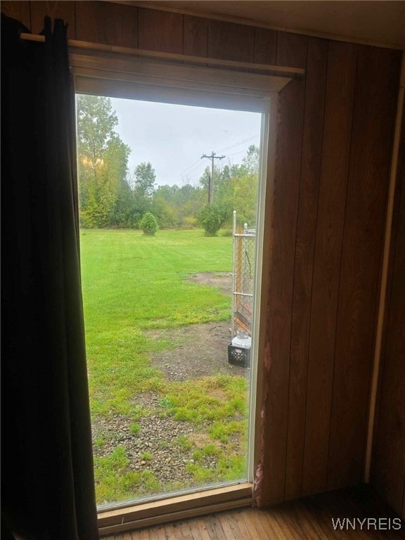 doorway to outside with wood-type flooring and wood walls