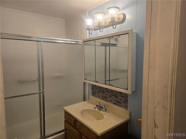 bathroom featuring crown molding, decorative backsplash, vanity, and a shower with shower door