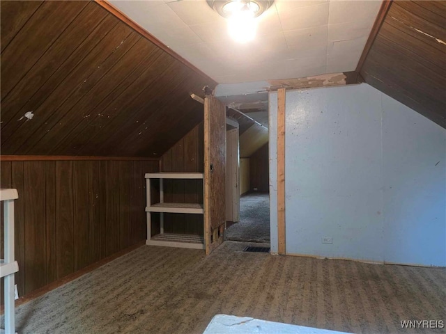 additional living space with carpet, lofted ceiling, and wood walls