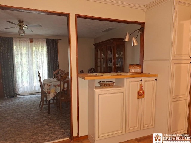 interior space featuring crown molding, ceiling fan, and carpet flooring