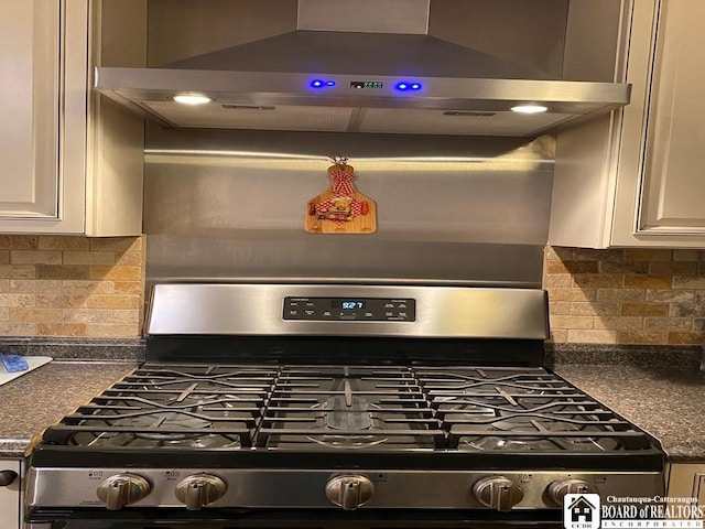 room details featuring tasteful backsplash, stainless steel gas range, extractor fan, and white cabinets