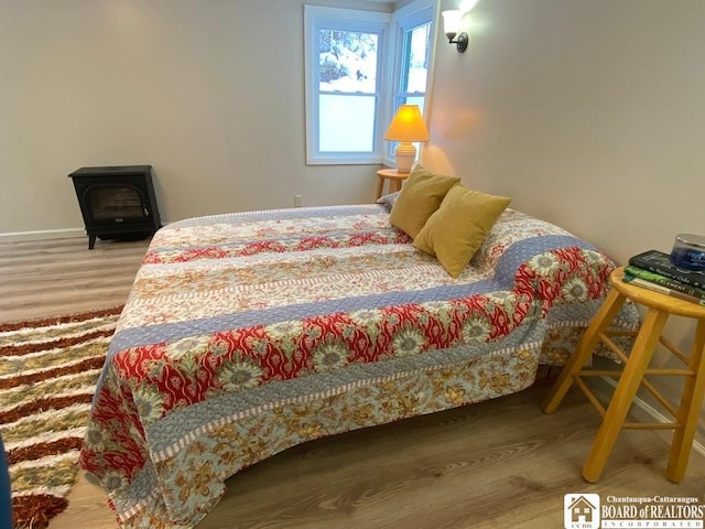 bedroom with wood-type flooring and a wood stove