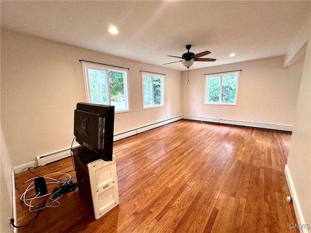 unfurnished room with ceiling fan, hardwood / wood-style flooring, plenty of natural light, and a baseboard heating unit