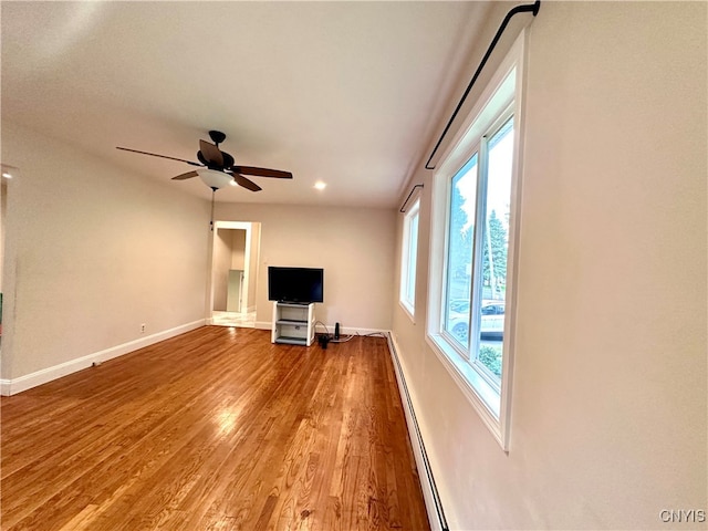 unfurnished living room featuring ceiling fan, baseboard heating, and hardwood / wood-style floors