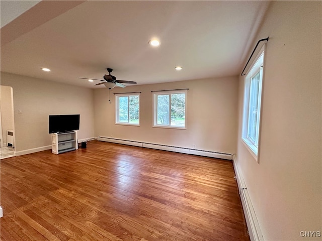 unfurnished living room with ceiling fan, hardwood / wood-style flooring, and a baseboard heating unit