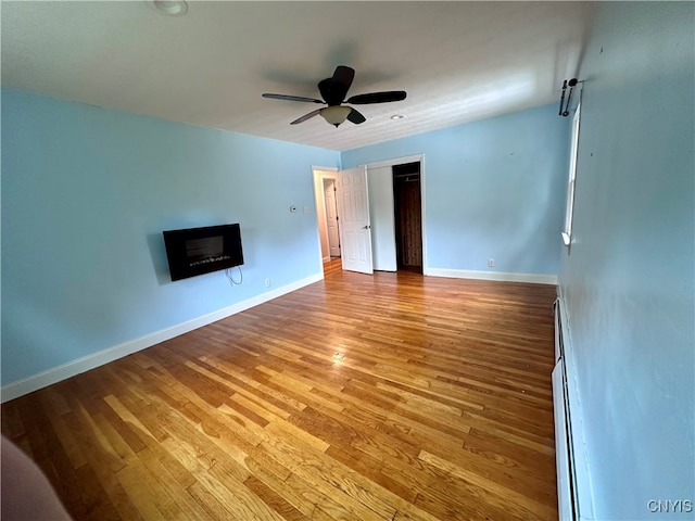 unfurnished living room with ceiling fan, baseboard heating, and hardwood / wood-style floors