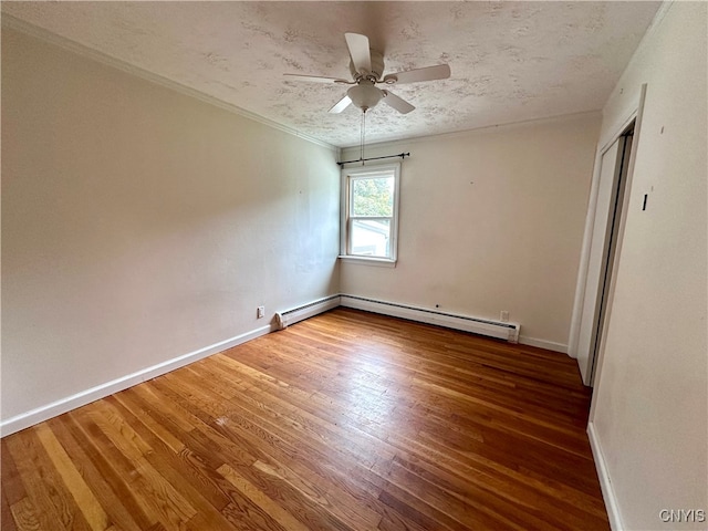 empty room featuring wood-type flooring, a textured ceiling, a baseboard radiator, ornamental molding, and ceiling fan