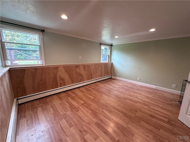 spare room with ornamental molding, wood-type flooring, and baseboard heating