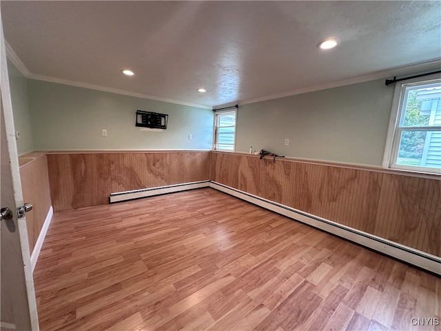 unfurnished room with wood walls, ornamental molding, baseboard heating, and hardwood / wood-style flooring