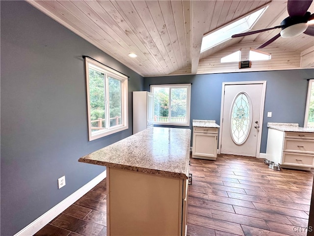 kitchen with wood ceiling, dark wood-type flooring, a kitchen island, vaulted ceiling with skylight, and ceiling fan