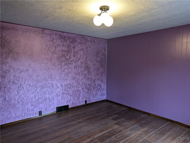 spare room with a textured ceiling and dark hardwood / wood-style flooring