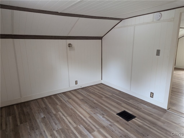 interior space featuring wood-type flooring, wooden walls, and lofted ceiling with beams