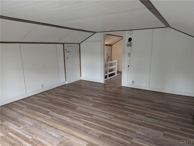 additional living space with hardwood / wood-style flooring, wood walls, and vaulted ceiling