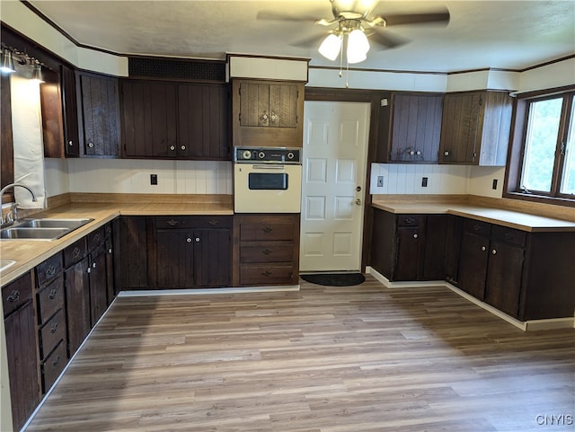 kitchen with ceiling fan, oven, dark brown cabinetry, and sink