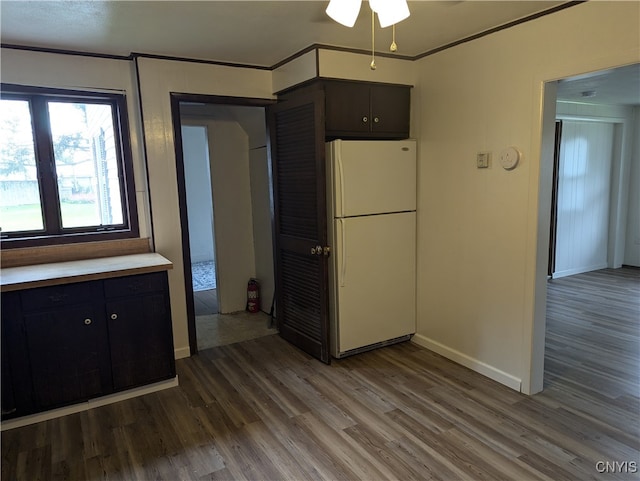 interior space with white fridge, dark brown cabinets, ceiling fan, hardwood / wood-style flooring, and ornamental molding